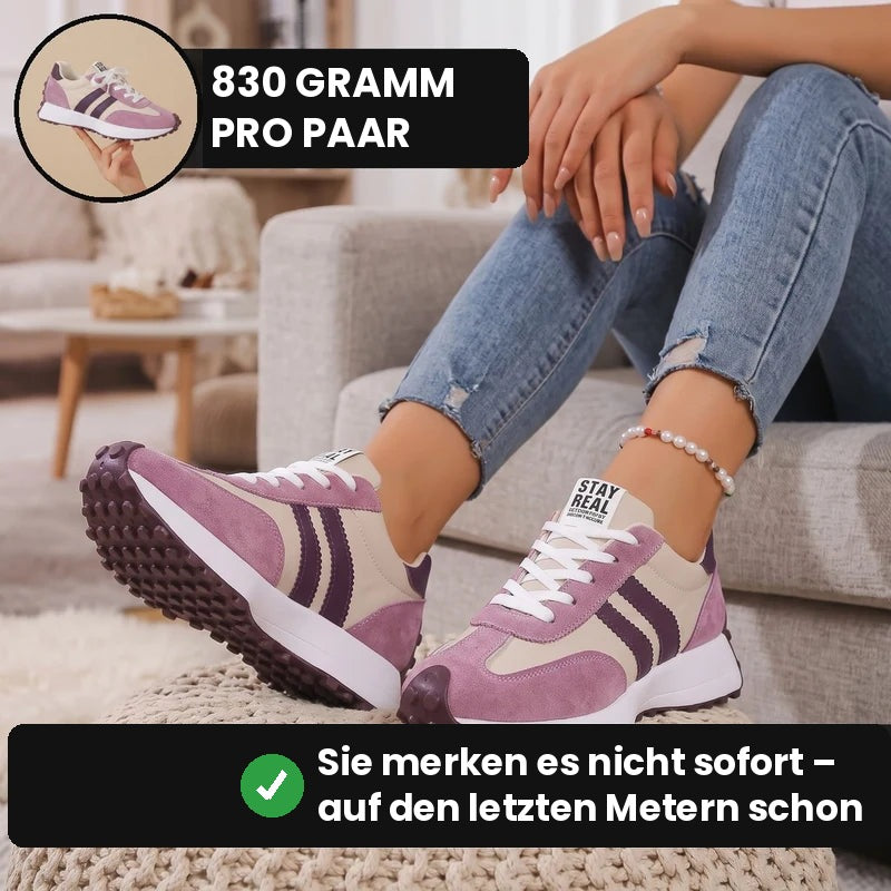 Frau sitzt entspannt auf dem Sofa und trägt den Fleureva Retro-Damensneaker in Rosa