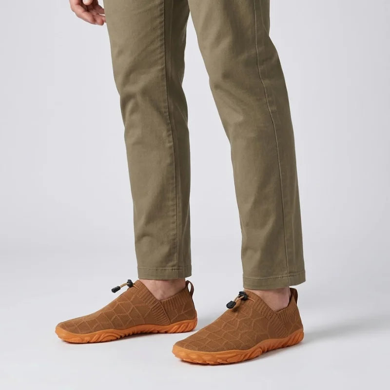 Person in Chinohose trägt braune Glidevo Slipper