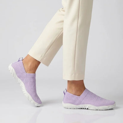Person in heller Hose geht in lila Glidevo Slippern